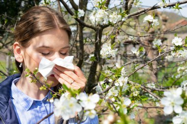Neşeli beyaz kadın bahar ağacı çiçeğine alerjik reaksiyon gösteriyor.