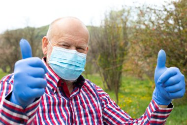 Dışarıdaki tekerlekli sandalyede oturan cerrahi maskeli yaşlı bir adam - enfeksiyon kapma riski