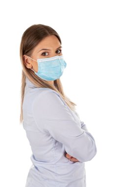 İzole edilmiş arka planda cerrahi maske takan beyaz bir kadının yan portresi.