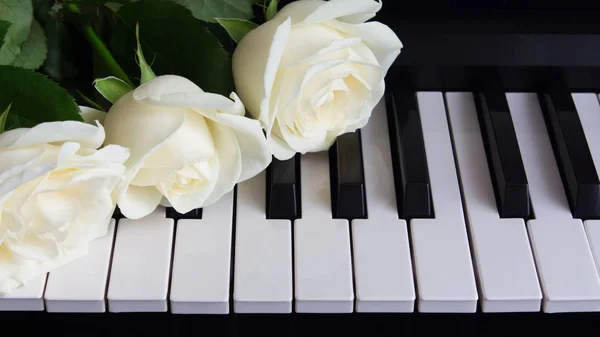 Bouquet of white roses on the piano. Flowers on a musical instrument. Birthday, March 8, international women\'s day, February 14, Valentine\'s day, mother\'s day, flower day. Card, gift, romance, love