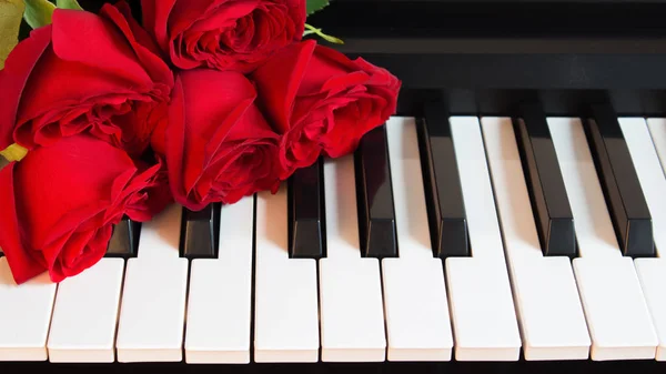Bukett röda rosor på pianot. Blommor på ett musikinstrument. Födelsedag, 8 mars, internationell kvinnodag, 14 februari, Alla hjärtans dag, mors dag, blomdag. Kort, gåva, romantik, datum kärlek — Stockfoto