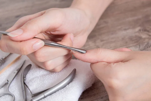 Manicure. Push back the cuticle with a metal pusher. Getting injured during a manicure. Skin care, hygiene. Spa, nail salon. Home care. Beauty.