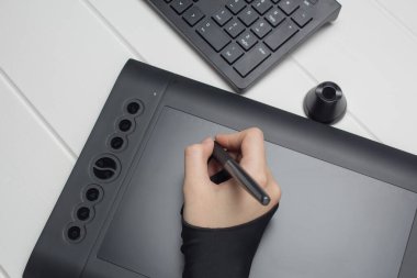 Grafik tasarımcısı dijital tablet üzerinde çalışıyor. El bir grafik tabletine çiziyor. Serbest çalışan, tasarımcı, çizer. Teknoloji, uzaktan kumanda, dış kaynak kullanımı. Grafik tableti için eldiven ve kalem. Proje,