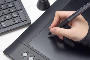 Grafik tasarımcısı dijital tablet üzerinde çalışıyor. El bir grafik tabletine çiziyor. Serbest çalışan, tasarımcı, çizer. Teknoloji, uzaktan kumanda, dış kaynak kullanımı. Grafik tableti için eldiven ve kalem. Proje