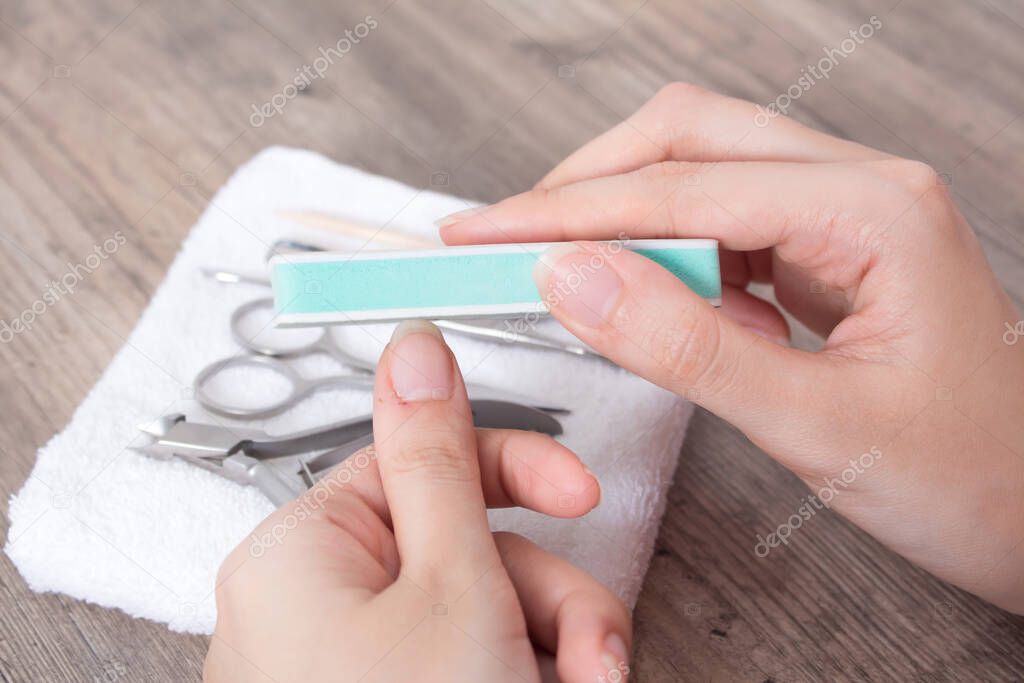 A woman polishes her nails. File your nails. Manicure, cuticle, hygiene, procedure. Hand care, home manicure. Nail salon, Spa, beauty.