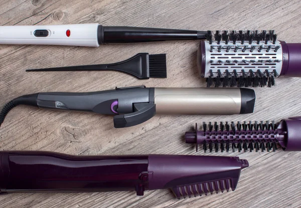 Ceramic Curling iron, hair brush on a wooden background. Hot styling, boar bristles, hair care. Beauty salon, styling, haircut. Beauty, fashion, style.