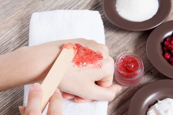 A woman applies a natural homemade scrub with a spatula. Skin care. Natural ingredients for making a scrub, sugar, cream, berry. Moisturizing, exfoliating, peeling. Home Cosmetics, Spa Treatment, Eco