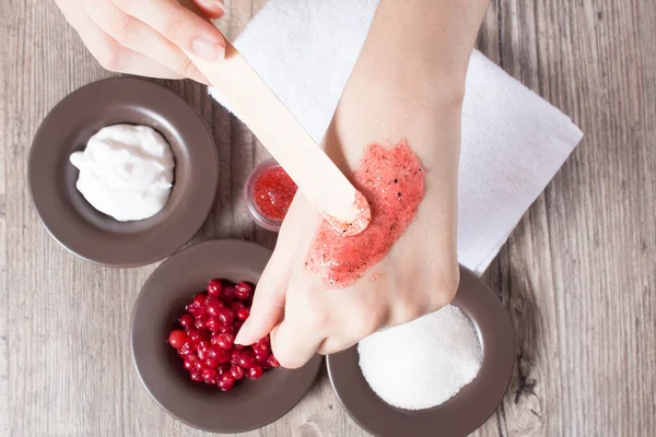 A woman applies a natural homemade scrub with a spatula. Skin care. Natural ingredients for making a scrub, sugar, cream, berry. Moisturizing, exfoliating, peeling. Home Cosmetics, Spa Treatment, Eco