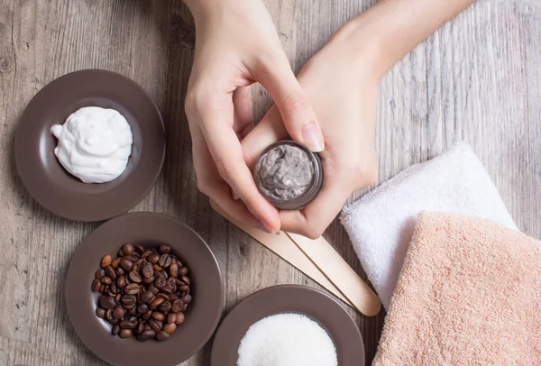 A young woman holds a jar of homemade coffee scrub. SPA, beauty. Ingredients for making a scrub, coffee beans, sugar, cream. Skin care.  Moisturizing, exfoliating, peeling. Home Cosmetics, Eco