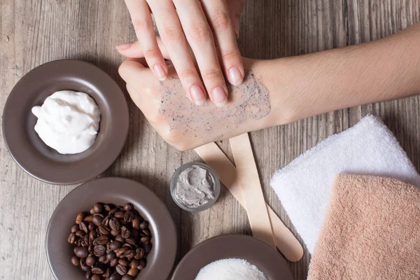 A woman applies a natural coffee scrub to the skin. Homemade scrub made of sugar, salt, cream and coffee. Beauty, Spa, skin care, aromatherapy. Moisturizing, peeling, exfoliation