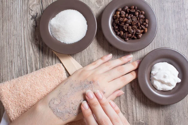 A woman applies a natural coffee scrub to the skin. Homemade scrub made of sugar, salt, cream and coffee. Beauty, Spa, skin care, aromatherapy. Moisturizing, peeling, exfoliation