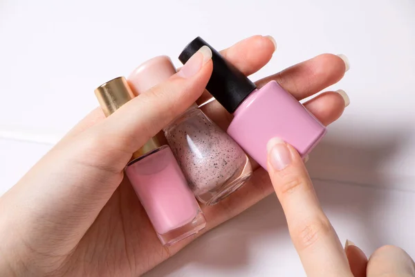 修指甲 一个女人拿着铁钉波兰人 女孩选择了指甲油的颜色 指甲油 指甲沙龙 Spa 家庭指甲护理 修指甲的工具 生活方式 — 图库照片