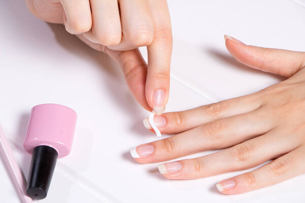 Manicure. A woman glues stickers on her nails for French manicure. The girl applies nail Polish. Nail care. Nail salon, procedure, SPA. Home nail care. Manicure tools. Beauty, nail art, Glamour.