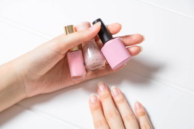 Manikür. Bir kadın tırnak cilası tutuyor. Kız ojenin rengini seçiyor. Fransızca, tırnak bakımı. Manikür salonu, prosedür, SPA. Evde tırnak bakımı. Manikür aletleri. Güzellik, yaşam tarzı, cazibe