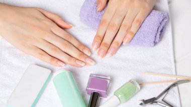 Manikür. Havlunun üzerinde kadın eli. Manikür aletleri, oje. Evde tırnak bakımı, SPA, güzellik. Uzun doğal tırnaklar. Güzellik salonu.