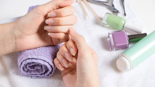 Havlunun üzerinde kadın eli. Manikür. Manikür aletleri, oje. Evde tırnak bakımı, SPA, güzellik. Uzun doğal tırnaklar. Güzellik salonu.