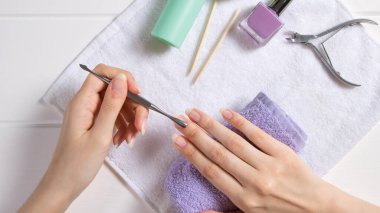 Manikür. Metal bir itici ile tırnak derisini geriye it. Manikür aletleri, ojeler, yağ. Evde tırnak bakımı, SPA, güzellik. Uzun doğal tırnaklar. Güzellik salonu.