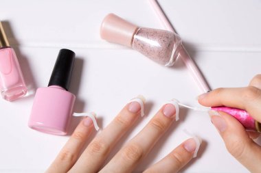 Bir kadın Fransız manikürü yapıyor. Cilt bakımı. Kız oje sürüyor. Manikür salonu, prosedür, SPA. Evde tırnak bakımı. Manikür aletleri. Güzellik, tırnak sanatı, ihtişam.