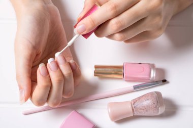 Manikür. Bir kadın tırnaklarını boyuyor. Kız oje sürüyor. Fransız. Manikür salonu, prosedür, SPA. Evde tırnak bakımı. Manikür aletleri. Güzellik, tırnak sanatı, ihtişam