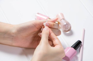 Bir kadın manikür için tırnaklarına yapışkan yapıştırıyor. Manikür. Kız oje sürüyor. Manikür salonu, prosedür, SPA. Evde tırnak bakımı. Manikür aletleri. Güzellik, tırnak sanatı, ihtişam.
