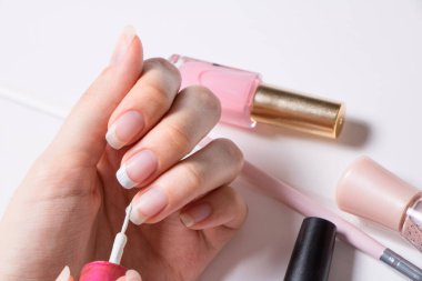 Manikür. Bir kadın tırnaklarını boyuyor. Kız oje sürüyor. Fransız. Manikür salonu, prosedür, SPA. Evde tırnak bakımı. Manikür aletleri. Güzellik, tırnak sanatı, ihtişam