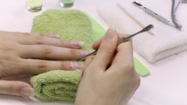 Manikür. Metal bir itici ile tırnak derisini geriye it. Manikür aletleri, ojeler, yağ. Evde tırnak bakımı, SPA, güzellik. Uzun doğal tırnaklar. Güzellik salonu.