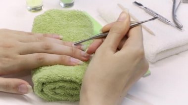 Manikür. Metal bir itici ile tırnak derisini geriye it. Manikür aletleri, ojeler, yağ. Evde tırnak bakımı, SPA, güzellik. Uzun doğal tırnaklar. Güzellik salonu.