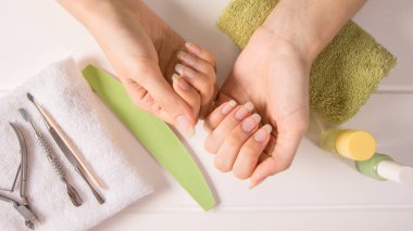 Manikür. Havlunun üzerinde kadın eli. Manikür aletleri, oje. Evde tırnak bakımı, SPA, güzellik. Uzun doğal tırnaklar. Güzellik salonu.
