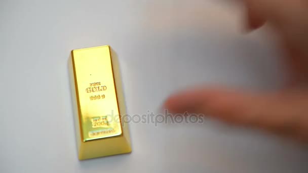 Слитки золота на белом столе — стоковое видео