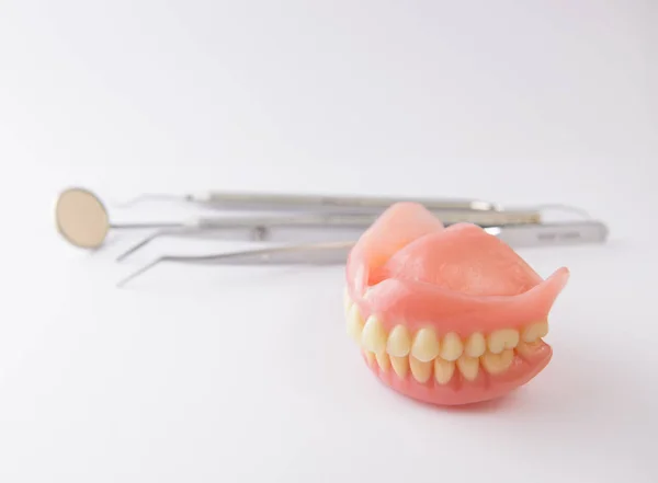 Prótesis dentales y herramientas dentales sobre fondo blanco — Foto de Stock