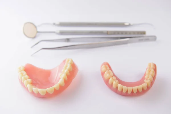 Набор фальшивых зубов и зубных инструментов на белом фоне — стоковое фото