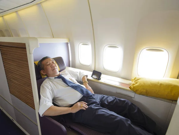 Hombre de negocios durmiendo en la primera clase de avión en cómodo asiento individual — Foto de Stock