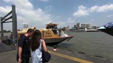 Bangkok, Tayland - 5 Mart 2018: İnsanlar bir sarı bayraklı turist teknesi olan Chao Phraya hızlı tekne, Chao Phraya Nehri üzerinde çalışan bir ulaşım hizmeti için bekleyen Prannok iskelede