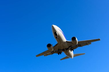 Üzerinde mavi gökyüzü olan bir uçak iniyor.