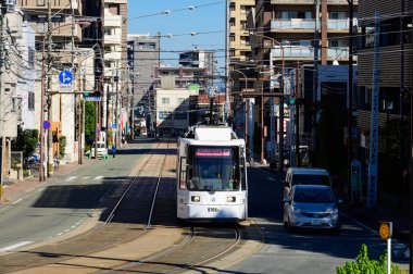 Kumamoto, Japonya - 15 Kasım 2019: Sokakta diğer araçlarla birlikte elektrikli tramvay