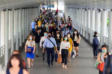 İş adamları yoğun saatlerde koronavirüs salgınını önlemek için cerrahi maske takıyorlar.