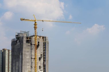 Mavi gökyüzüne karşı inşaat halindeki vinç ve bina