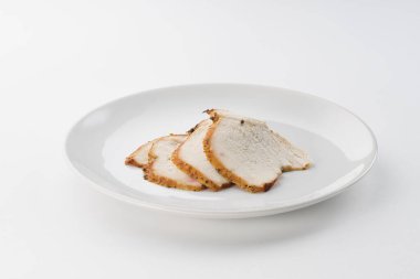 Beyaz arka planda bir tabakta kesilmiş haşlanmış et.