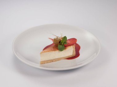 Böğürtlenli cheesecake ve beyaz arka planda nane yaprağı.