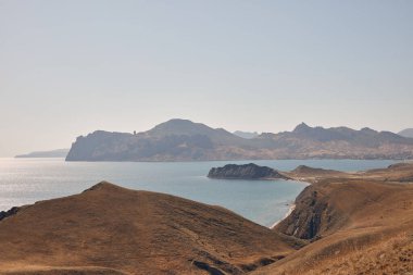 Güneşin altında denizin arka planında güzel yeşil tepeler
