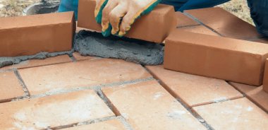 Bir adam tuğla bir duvar inşa eder. Brick çözeltiyi koydu. Yapılandırma