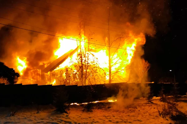 Casa se está quemando, una casa de fuego en un pueblo, bomberos saliendo — Foto de Stock