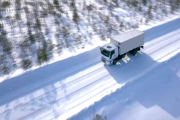 lorry with a wagon rides along the road in winter. Winter road for a truck.