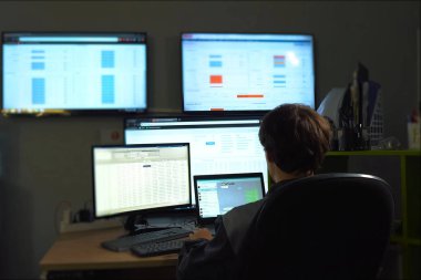 Hacker monitörün arkasında oturuyor ve çalışıyor. Bilgisayar teknisyeni ve programcının işi..