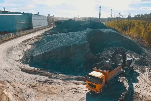Una excavadora vierte arcilla en un camión volquete para la producción de ladrillos . — Foto de Stock