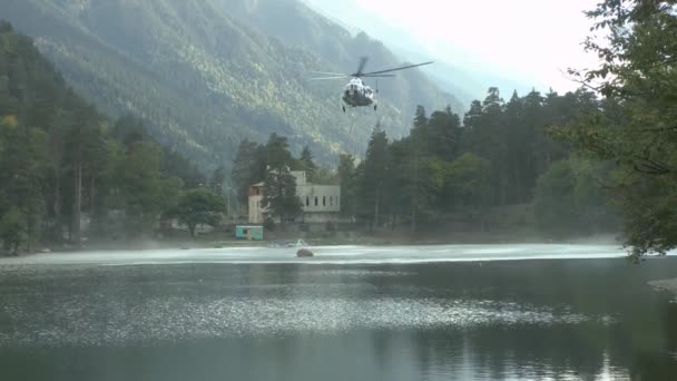 Вертолет МЧС собирает воду для тушения лесного пожара — стоковое видео