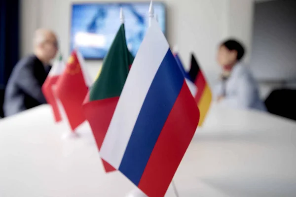 Blur effect. Meeting of management, meeting of directors. International commission, table with flags of EU, Russia and other countries.