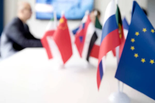 Blur effect. Meeting of management, meeting of directors. International commission, table with flags of EU, Russia and other countries.