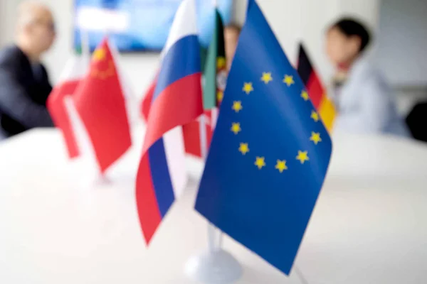 Blur effect. Meeting of management, meeting of directors. International commission, table with flags of EU, Russia and other countries.