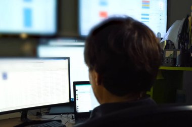 Hacker monitörün arkasında oturur ve çalışır. Bilgisayar teknisyeni ve programcının işi..